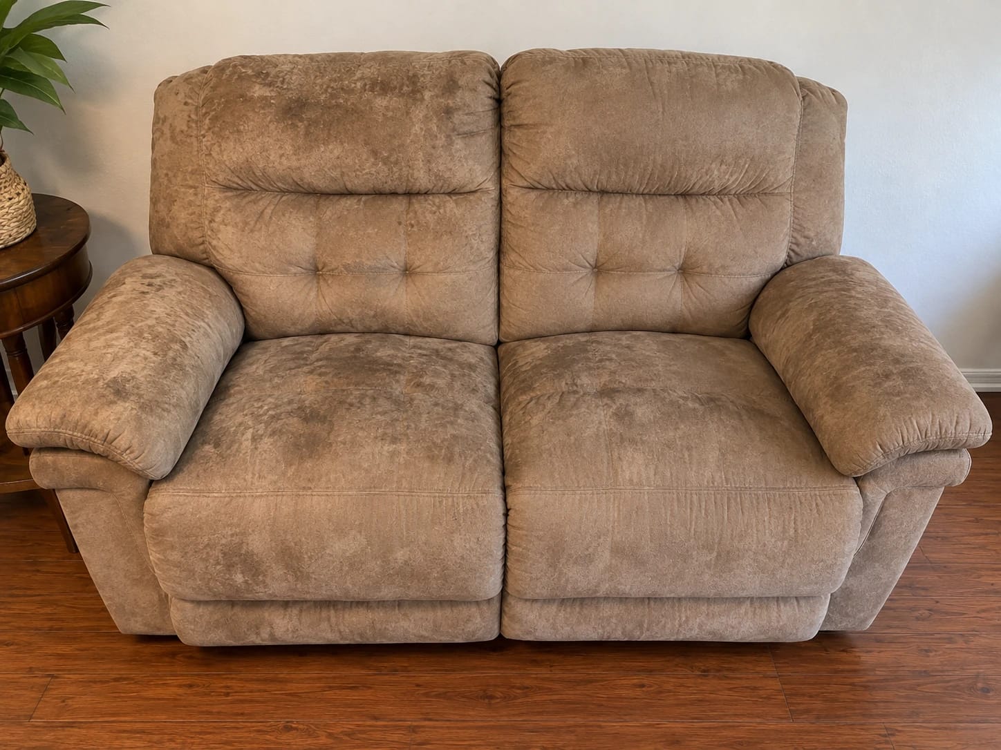 Before — tan reclining loveseat with dark stains on the cushions and arms